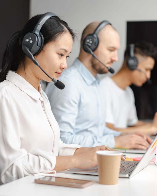 Contact center agents with headsets working at laptops